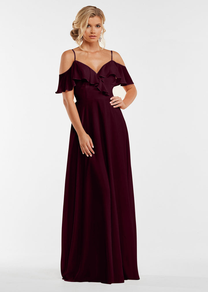 A woman models the Avery Austin 83013: a floor-length, off-the-shoulder burgundy gown with a ruffled neckline, posed against a plain white background.