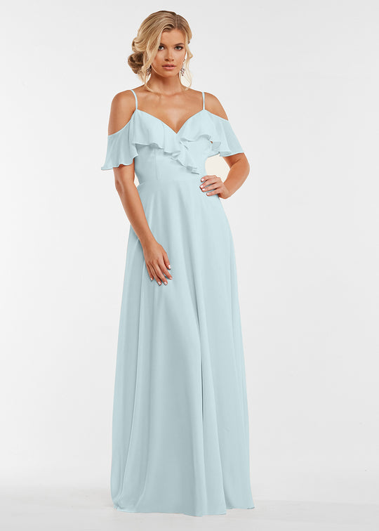 A woman models the Avery Austin TH-83013 dress in sky blue. The off-the-shoulder, floor-length gown features a ruffled neckline. She poses with one hand on her hip, hair in loose waves, against a white background.