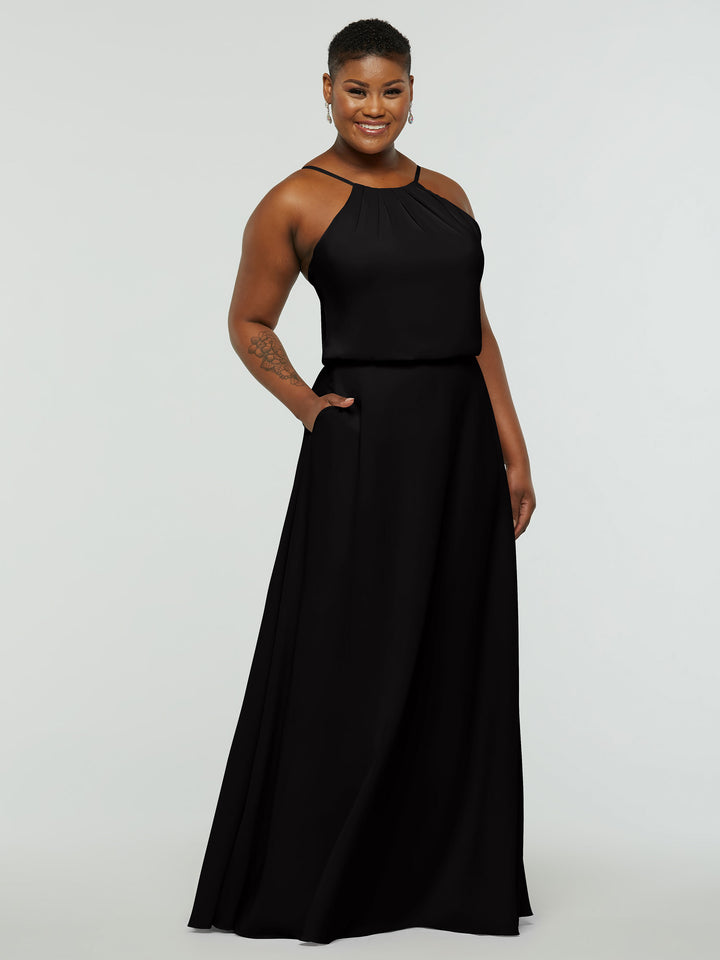 A smiling person wears the Avery Austin 83015, a sleeveless floor-length black A-line dress with a halter neck and pockets, standing before a plain light background.