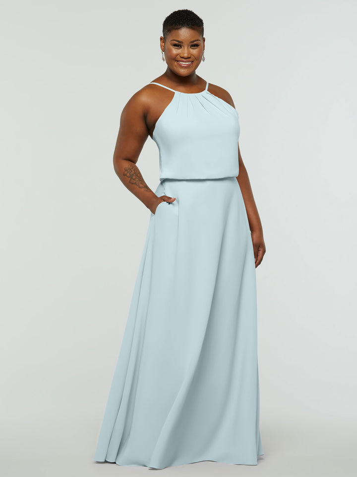 A person smiles while wearing the Avery Austin 83015 sleeveless A-line dress in Sky Blue with a halter neck and pockets, standing against a plain white background.