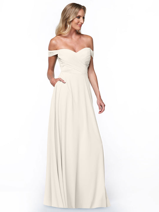 A woman models Avery Austin's 83018, an off-the-shoulder ivory gown with a fitted bodice, A-line skirt, floor-length fabric, and side pockets, standing against a plain white background.