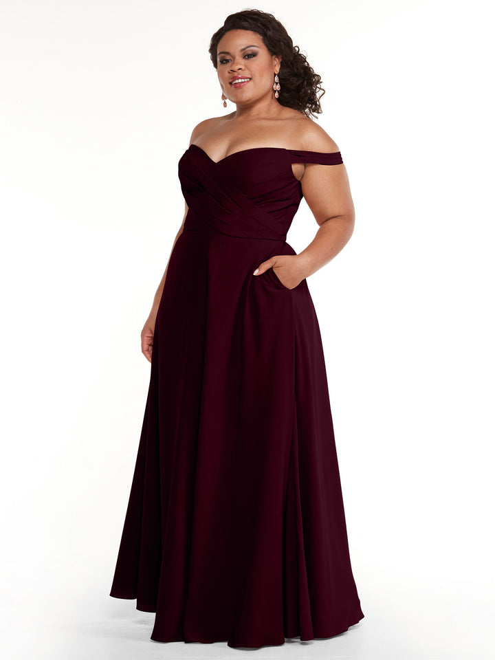 A woman stands confidently against a plain white background, smiling with one hand in her pocket, wearing Avery Austin&