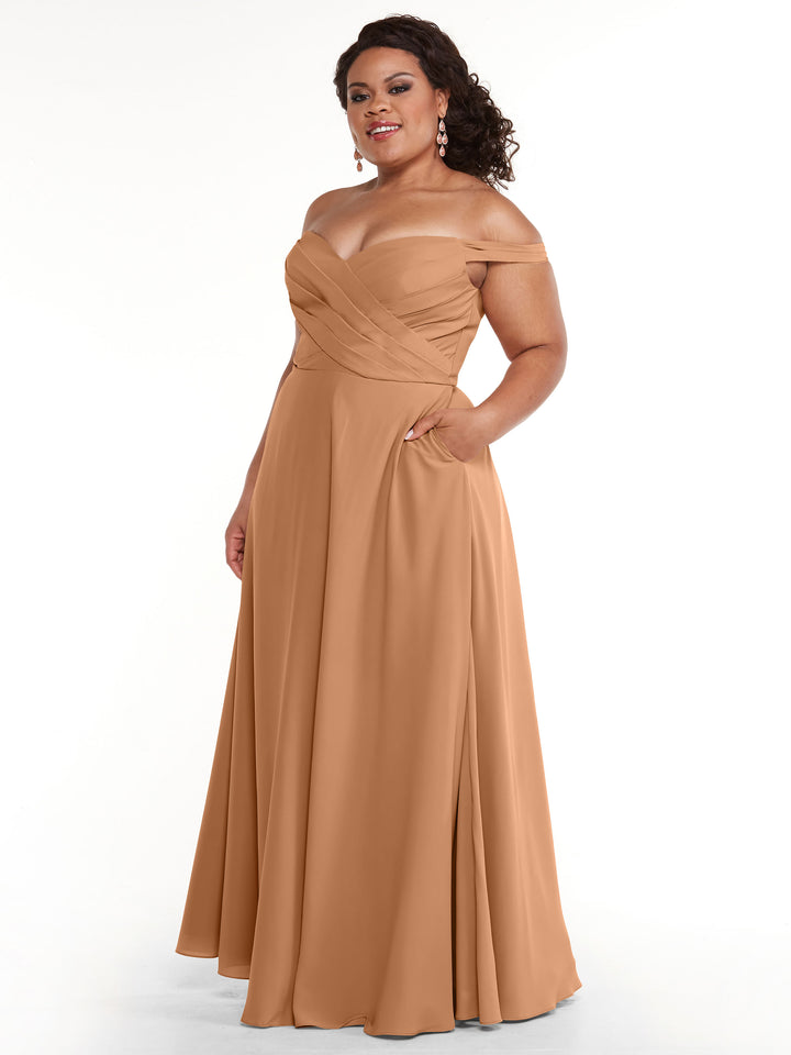 A woman models the Avery Austin 83018, a copper off-the-shoulder A-line dress with pockets, standing against a white background. Her curly hair frames her face, she wears dangling earrings, and one hand rests casually in her pocket.