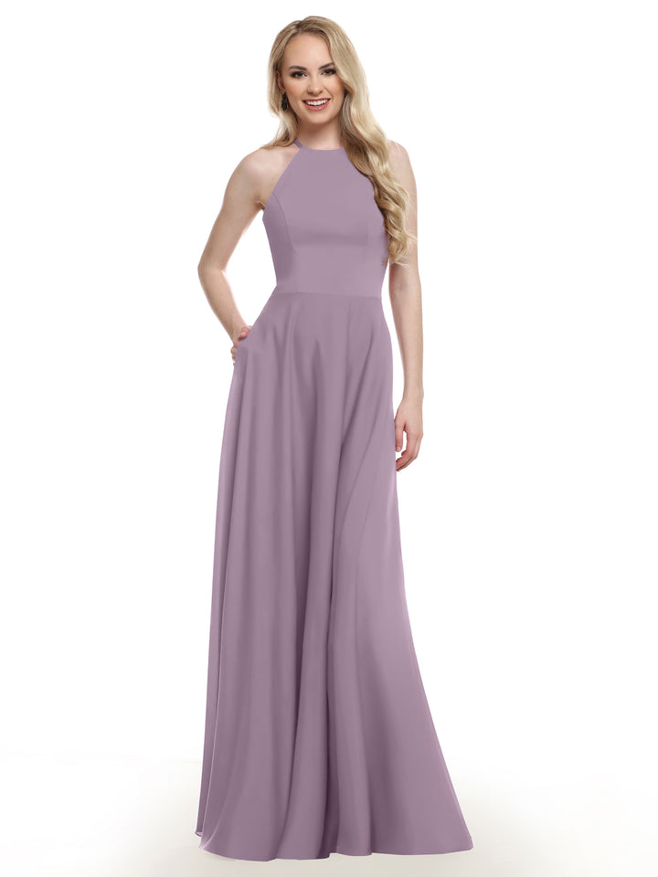 A woman with long, wavy blonde hair smiles in front of a white background, wearing Avery Austin&
