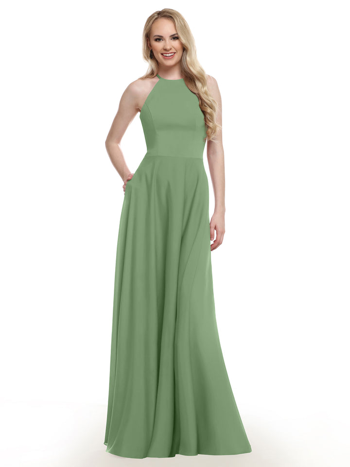 A smiling woman with long blonde hair models Avery Austin’s 83022, a sleeveless, floor-length light green A-line dress, posing with one hand in her pocket against a plain white background.