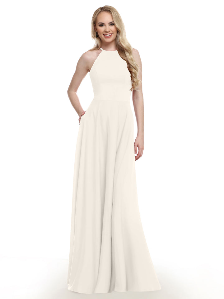 A woman stands and smiles against a white background, wearing Avery Austin’s 83022—a sleeveless, floor-length white gown featuring a fitted bodice and flared A-line skirt.