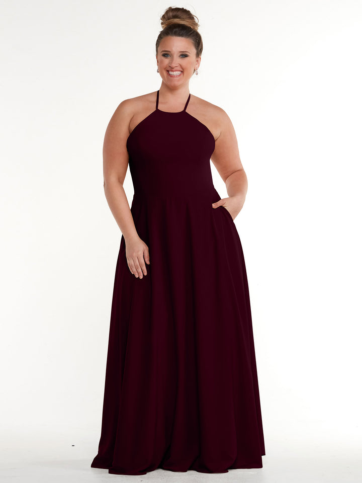 A woman stands smiling against a white backdrop, wearing Avery Austin&