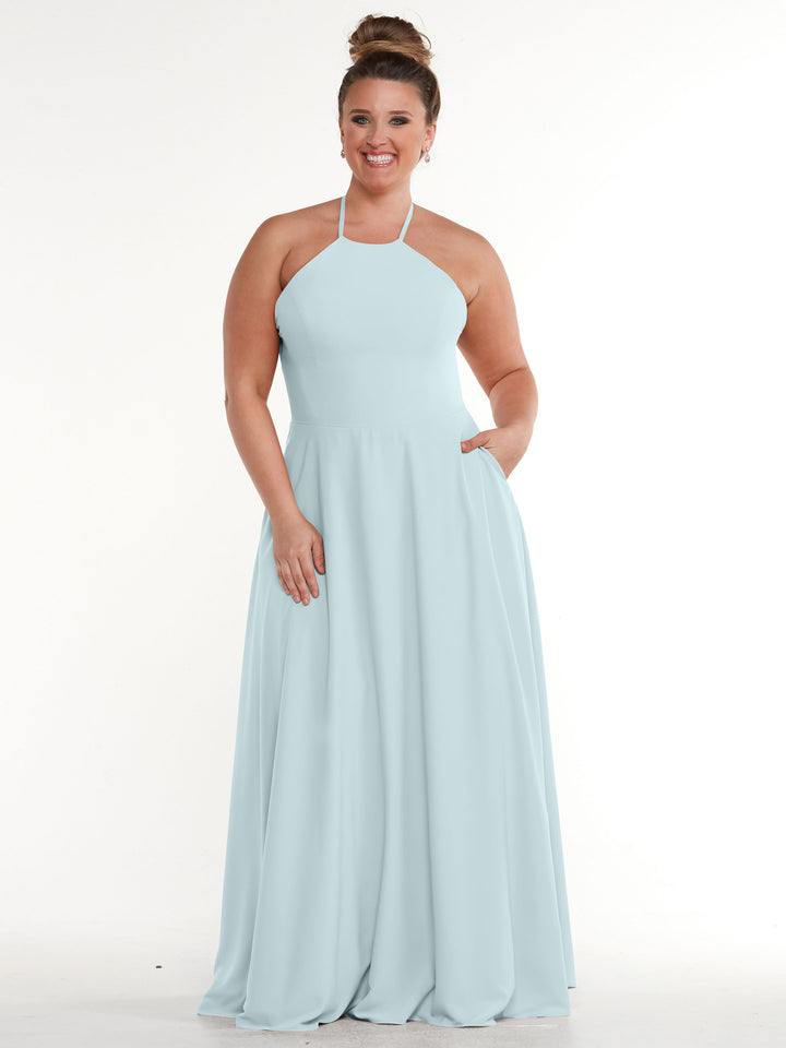 A woman stands smiling with one hand in her pocket, modeling Avery Austin&