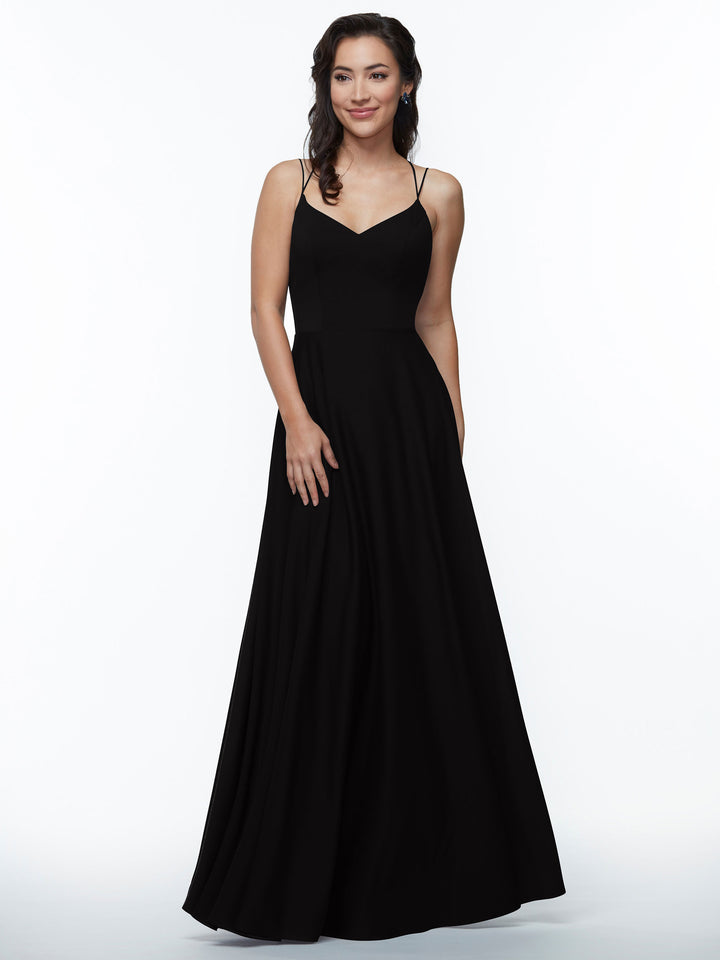 A woman poses against a white background in the Avery Austin 83024 A-Line dress with double spaghetti straps. Her loose waves and gentle smile complement the look, with one hand by her side and the other touching the dress.
