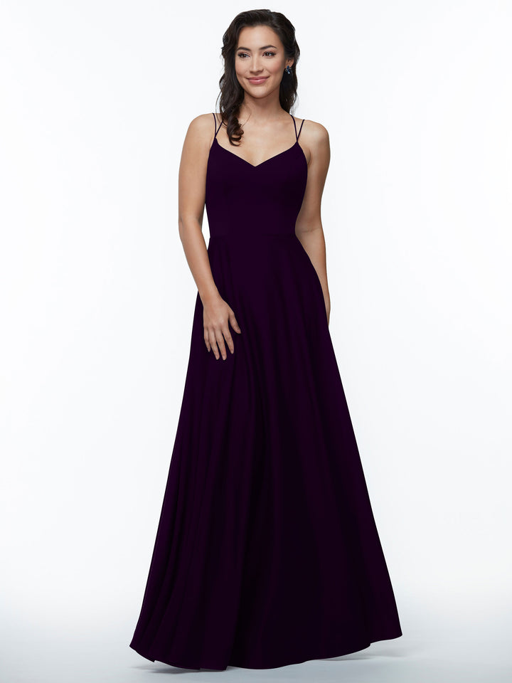 A woman wearing the Avery Austin 83024, an elegant floor-length deep purple A-line dress with double spaghetti straps, stands against a white background, smiling gently with one hand by her side and the other touching the dress.