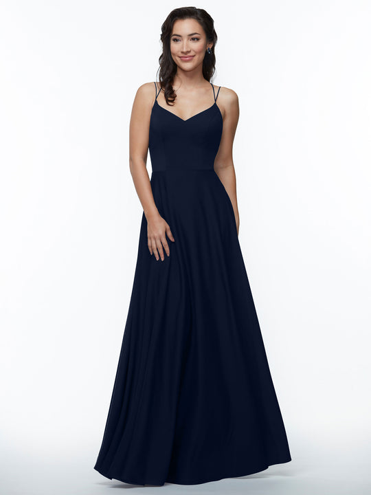 A woman in an Avery Austin TH-83024 sleeveless A-line dress with double spaghetti straps in Midnight stands against a white background, smiling with one hand at her side.