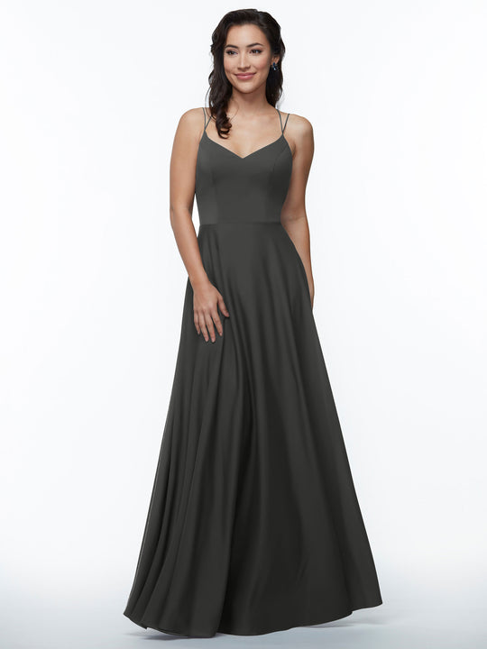 A woman with wavy dark hair smiles gently while wearing Avery Austin's elegant A-Line dress (style 83024) in dark gray, featuring double spaghetti straps and a flared skirt, against a white background.