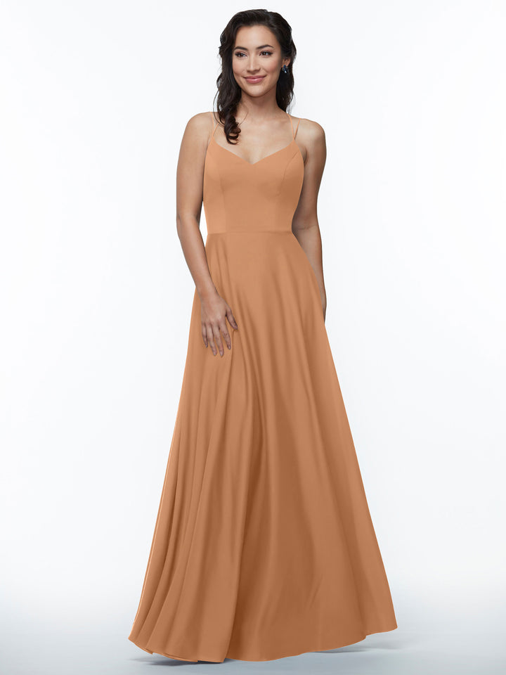 A woman stands and smiles in the Avery Austin 83024, an elegant floor-length A-line dress with double spaghetti straps and a fitted bodice, posing against a plain white background.