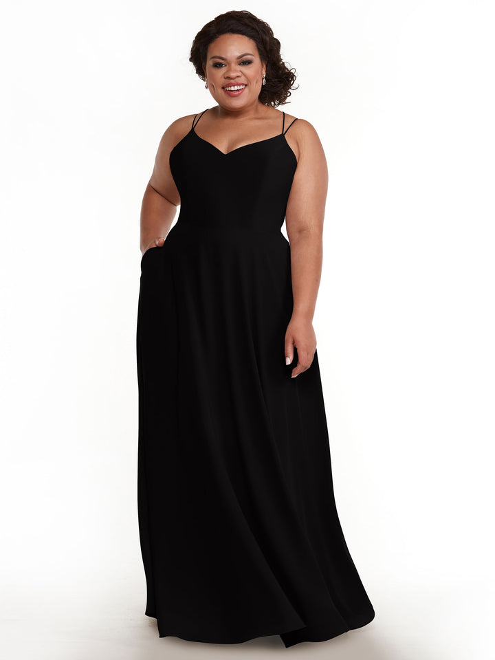 A woman with curly hair smiles against a white background, wearing Avery Austin&