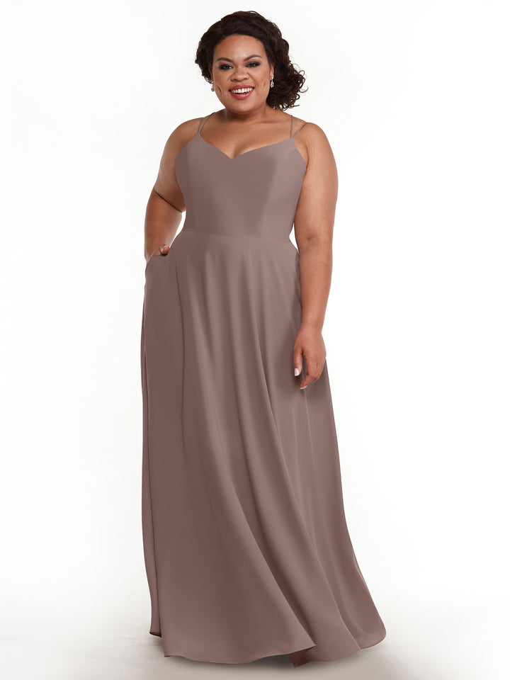 A smiling woman with curly hair wears the Avery Austin TH-83024 A-Line dress in Vintage Mauve, featuring double spaghetti straps and a V-neckline, standing against a plain white background.