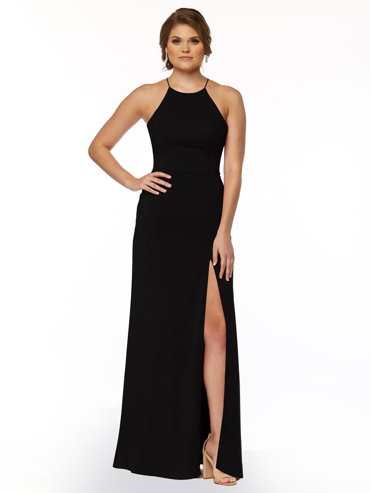 A woman models Avery Austin’s 83026: a sleeveless, floor-length black halter dress with a high neckline and thigh-high slit, paired with beige heels against a plain white background.