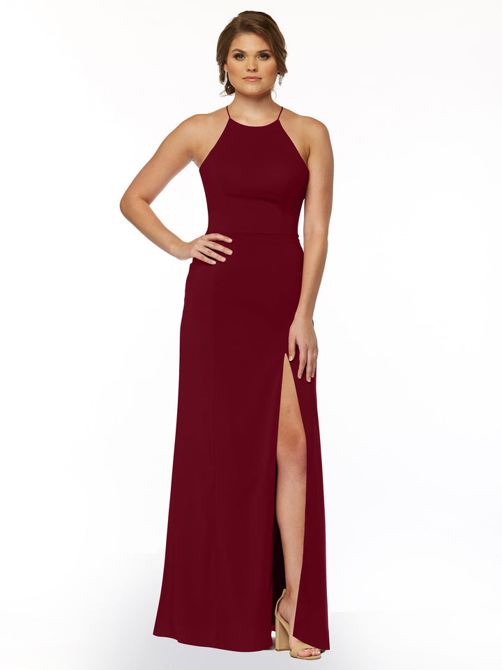 A woman poses against a white background wearing the Avery Austin 83026, a sleeveless floor-length burgundy sheath dress with a halter neck and thigh-high front slit.