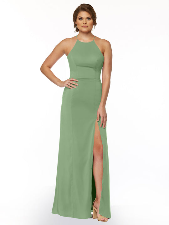 A woman models Avery Austin’s 83026: a sleeveless, light green sheath dress with a halter neck and front slit, paired with strappy high-heeled sandals, standing against a white background.