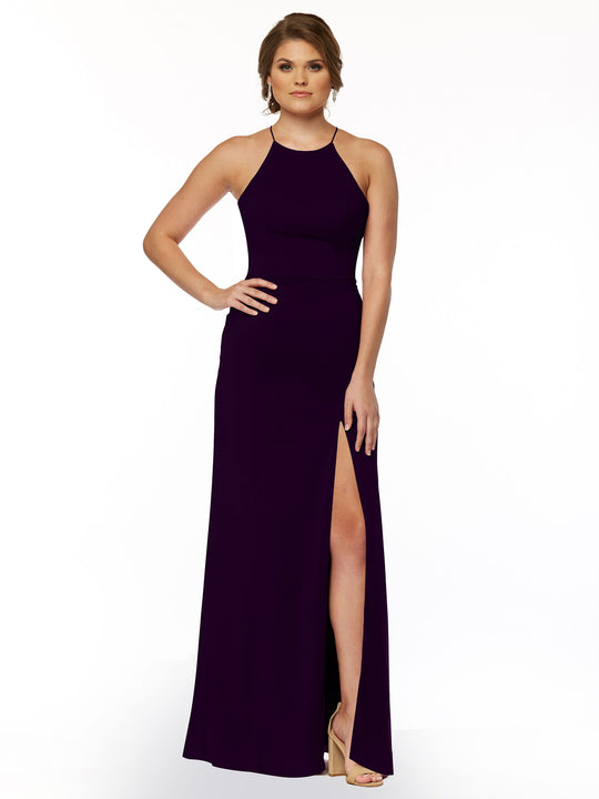 A woman models Avery Austin 83026, a sleeveless floor-length dark purple sheath dress with a halter neck and front slit, against a white background, one hand on her hip and wearing nude high-heeled sandals.