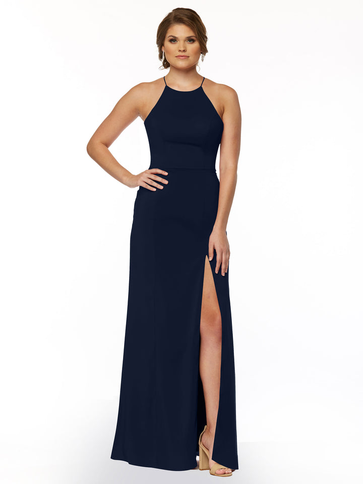 A woman models Avery Austin style 83026: a sleeveless navy blue sheath dress with a halter neck and thigh-high front slit, styled with nude heels and minimal jewelry against a white background.