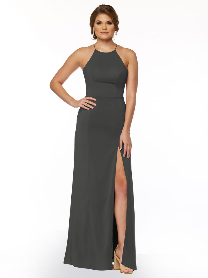 A woman poses with one hand on her hip, wearing Avery Austin’s TH-83026: a sleeveless dark gray sheath dress with a high neckline and thigh-high front slit, paired with nude high heels. Her short hair is stylishly done.