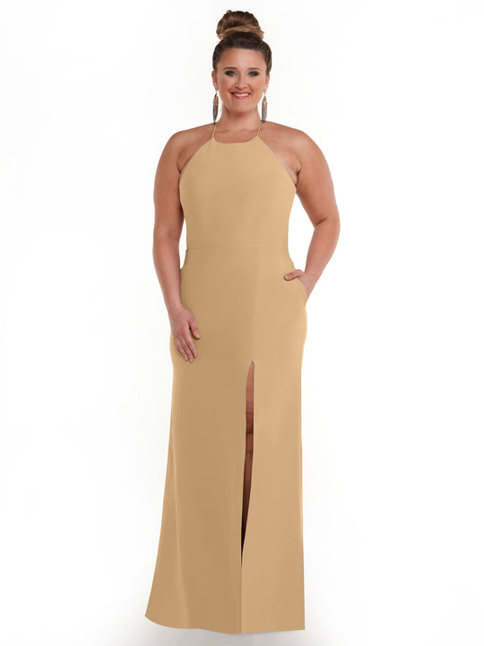 A woman smiles in the Avery Austin 83026 dress—a tan, floor-length sheath with a front slit and halter neck. Her hair is in a bun, with large hoop earrings, posing against a plain white background.