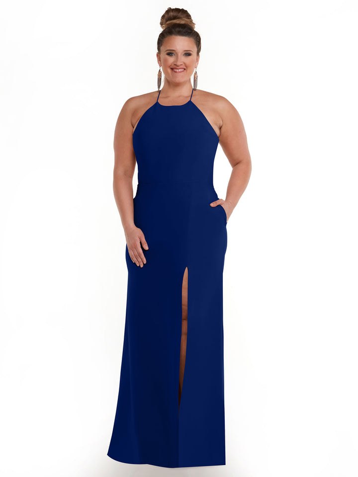 A woman smiles against a white background, wearing Avery Austin’s 83026—a sleeveless, floor-length navy blue sheath dress with a high neckline and front slit. Her hair is styled in an updo and she accessorizes with hoop earrings.