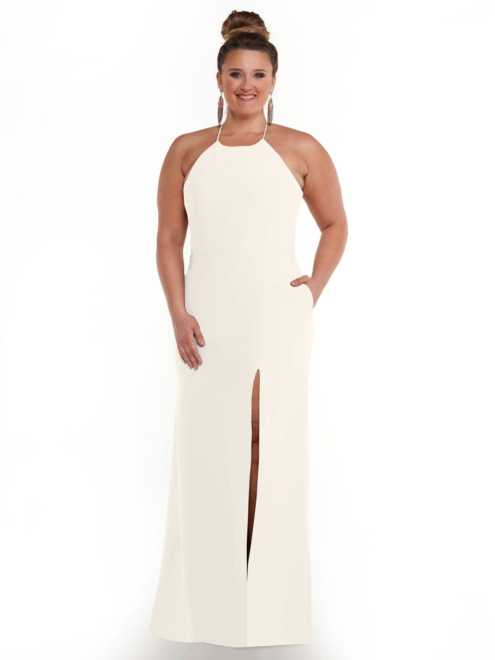 A woman poses against a white background in the Avery Austin 83026—a sleeveless, floor-length white halter neck dress featuring pockets and a high front slit, with one hand in her pocket.