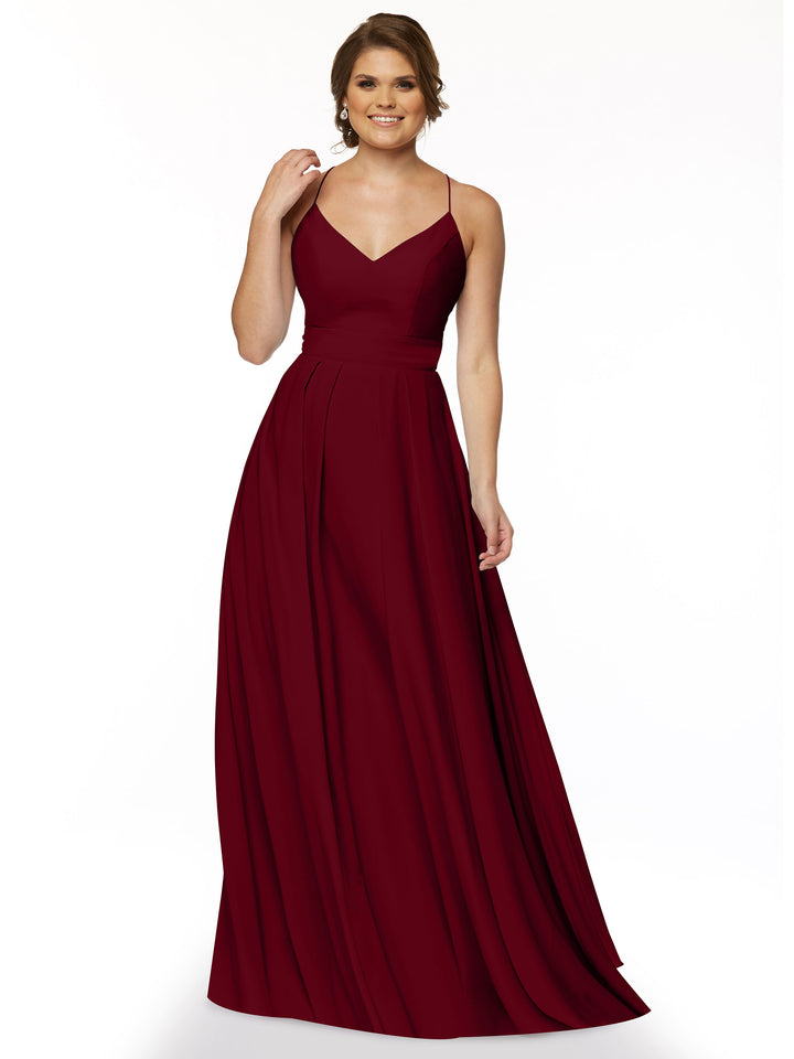 A woman models Avery Austin style 83027, a sleeveless, floor-length A-line gown in deep red with a fitted bodice and flared skirt. She smiles with light brown wavy hair against a plain white background.