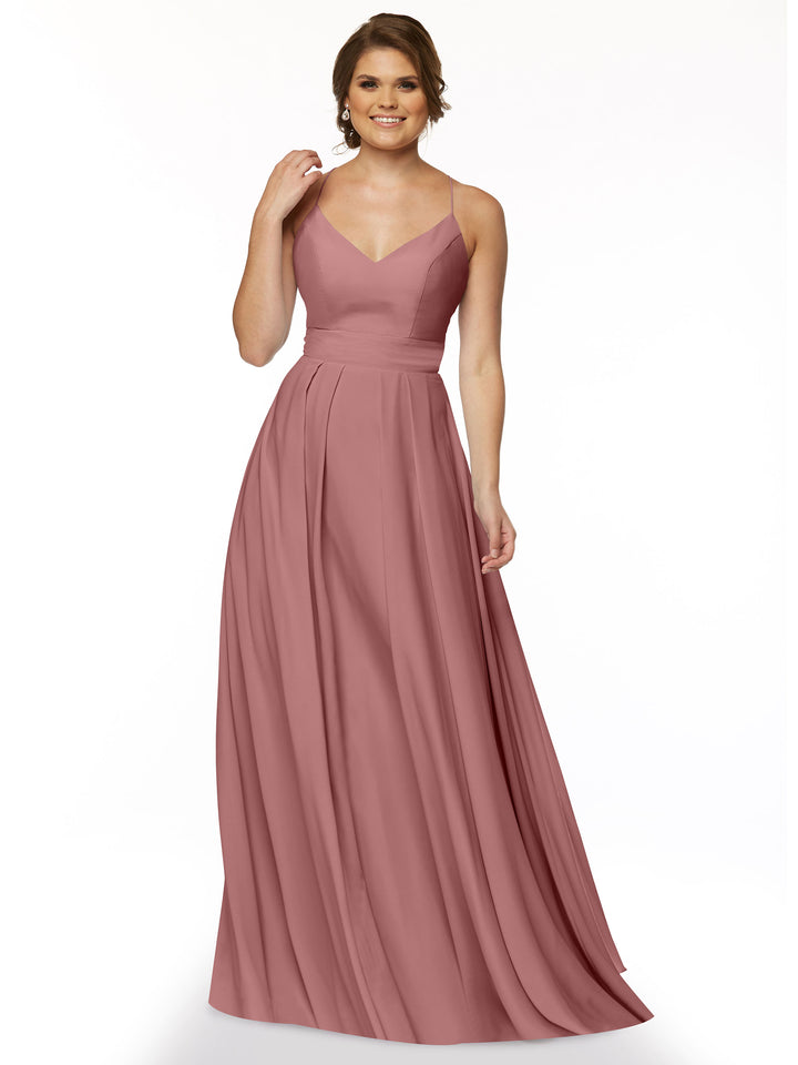 A woman smiles against a plain white background, wearing Avery Austin’s 83027—a sleeveless, floor-length dusty rose A-line dress with a fitted bodice, V-neckline, and flowing skirt.