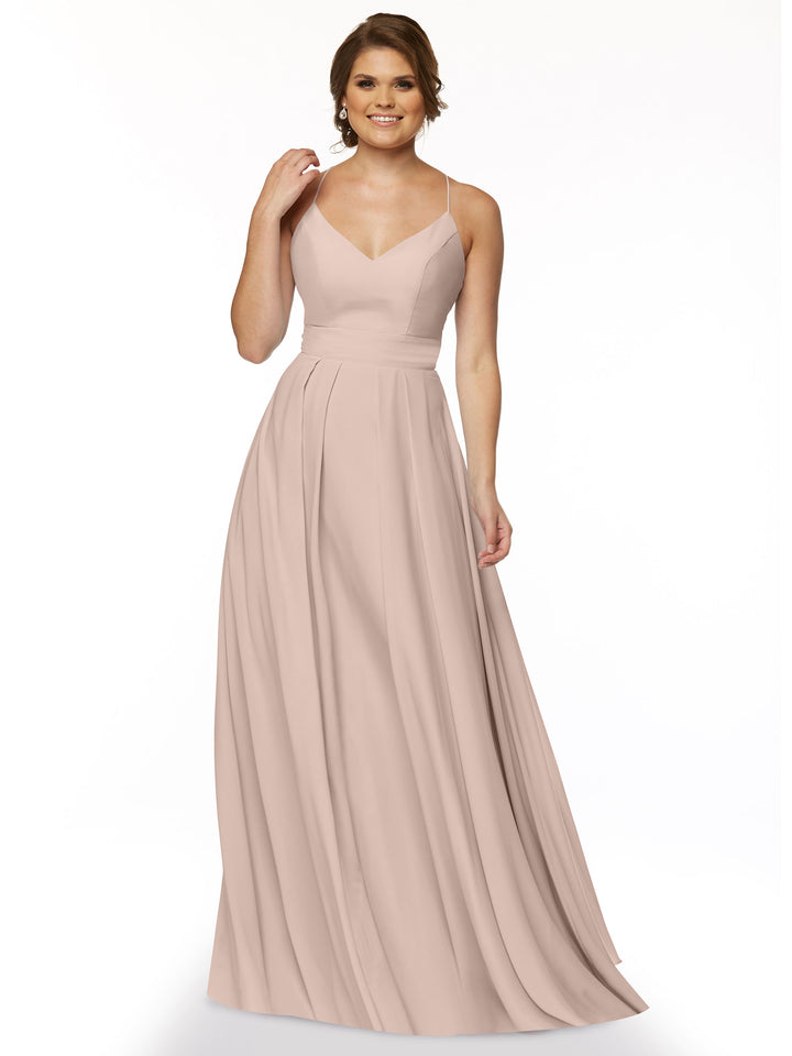 A woman smiles against a white background wearing Avery Austin’s 83027, a sleeveless A-line dress in rose pink with a fitted bodice and V-neckline. Her hair is up as she holds one hand near her neck.