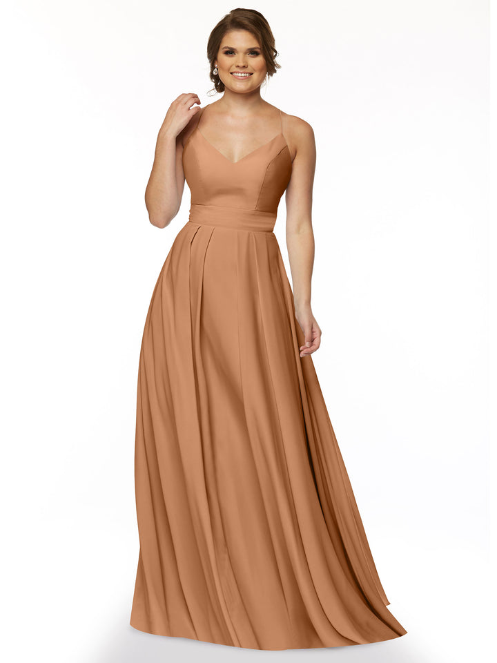 A woman in Avery Austin’s 83027, a sleeveless, floor-length A-Line dress with a fitted bodice and flowing skirt in light brown, stands smiling against a plain white background.