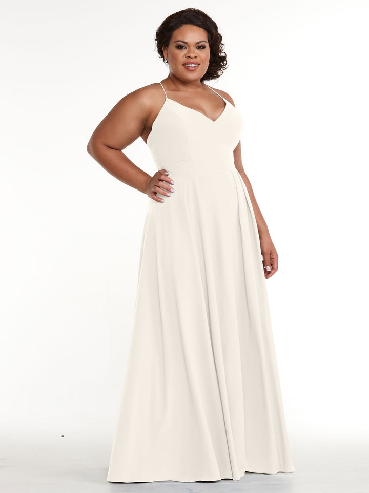 A woman confidently poses with one hand on her hip in the Avery Austin 83027, a sleeveless, floor-length A-line dress with spaghetti straps, against a plain white background.