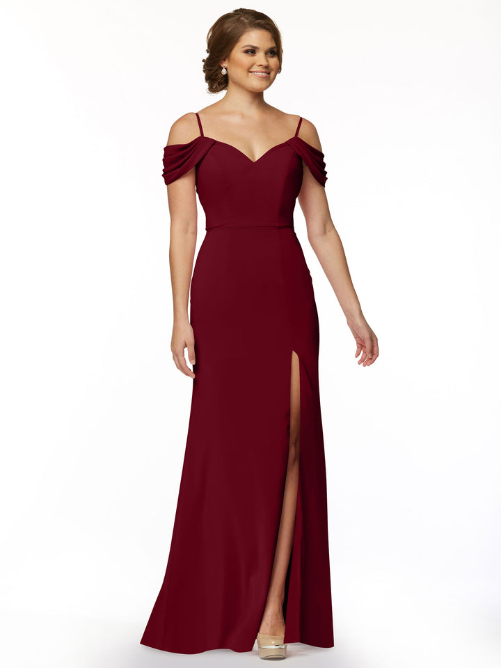 A woman poses against a white background in Avery Austin style 83029, a fitted burgundy off-the-shoulder dress with spaghetti straps and a thigh-high slit.