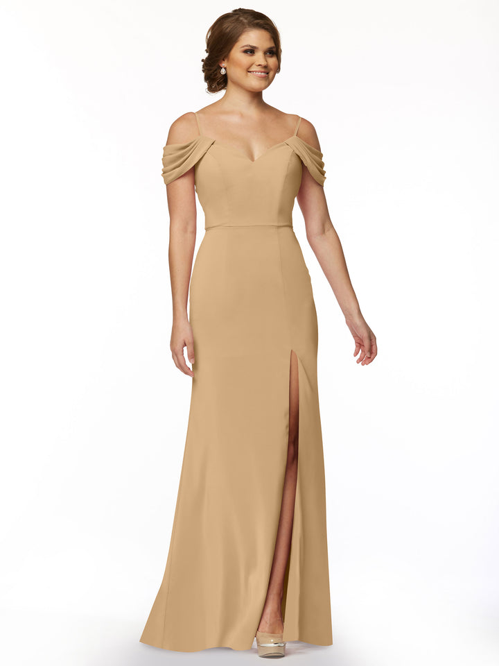 A woman wearing the Avery Austin 83029 tan off-the-shoulder dress with draped sleeves and a thigh-high slit smiles against a plain white background.
