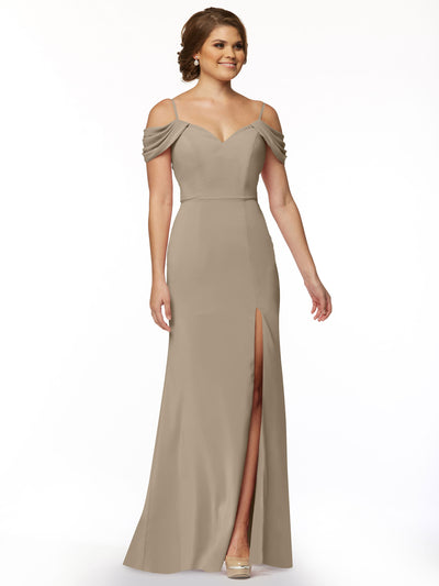 A woman models Avery Austin’s 83029: a taupe, floor-length off-the-shoulder dress with draped sleeves, fitted bodice, and thigh-high slit, standing against a plain white background.