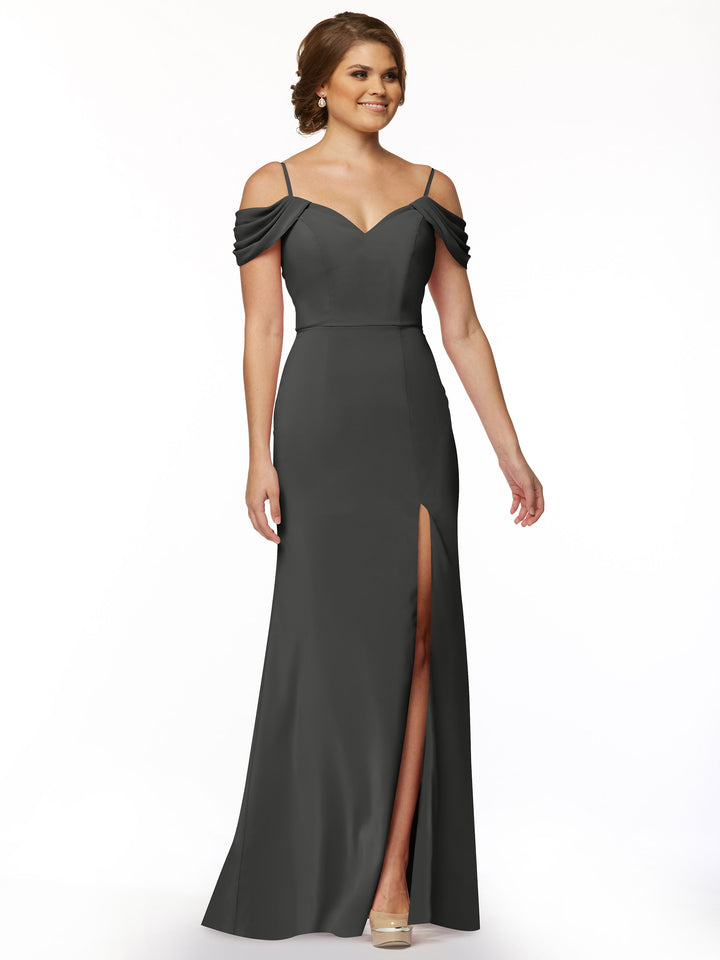 A woman models Avery Austin’s 83029, a floor-length dark gray off-the-shoulder gown with thin spaghetti straps, sweetheart neckline, and thigh-high slit, standing against a plain white background.