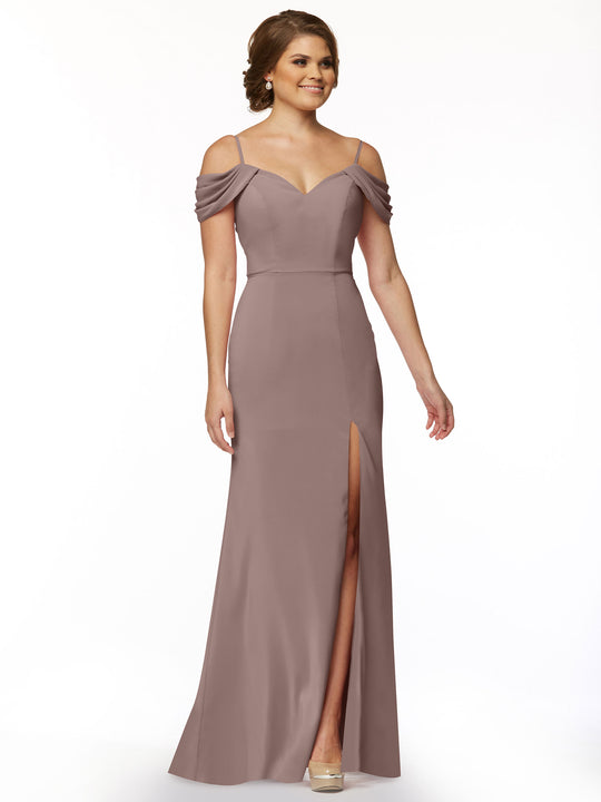 A woman wearing Avery Austin’s TH-83029—a mauve, floor-length off-the-shoulder dress with draped sleeves, sweetheart neckline, and thigh-high slit—stands smiling against a plain white background with her hair styled up.