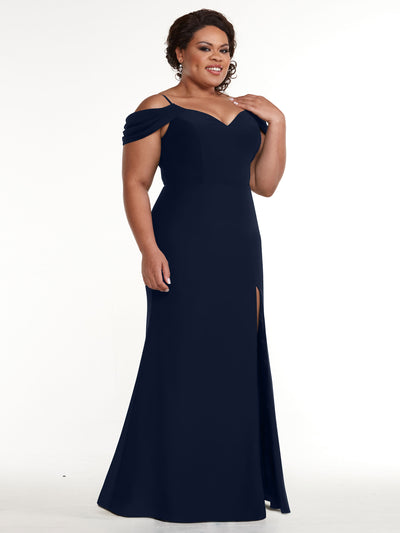 A woman models Avery Austin's 83029, a floor-length navy blue off-the-shoulder dress with a sweetheart neckline and thigh-high slit, posing confidently against a plain white background.