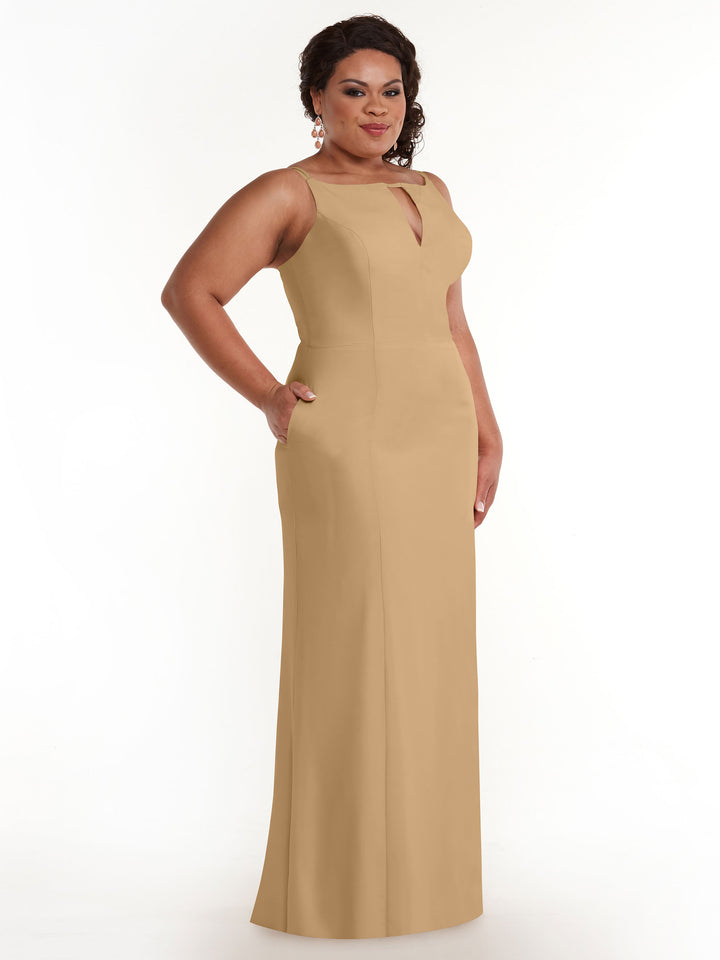 A woman models Avery Austin’s sleeveless, floor-length beige sheath dress (83030) with a keyhole neckline, standing against a white background and smiling with one hand on her hip.