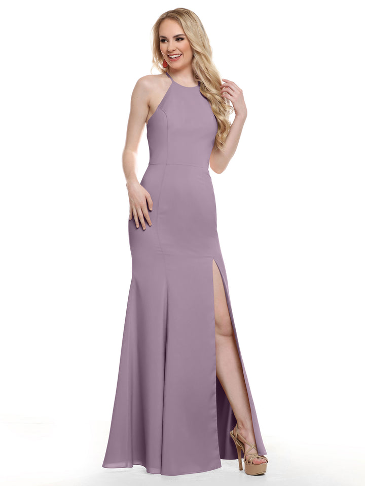 A woman poses in Avery Austin style 83031—a sleeveless, floor-length lavender halter dress with a high neckline and thigh-high slit—smiling in heels with her hand in her hair against a white background.