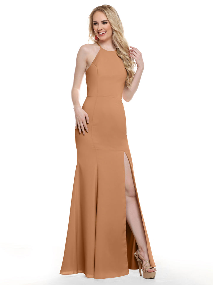 A woman with long blonde hair poses and smiles in the Avery Austin 83031, a fitted floor-length tan evening gown with a high slit and strapped back, set against a white background.