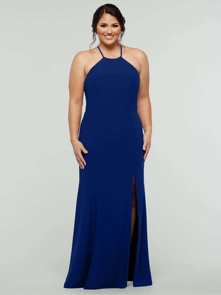A woman smiles in the Avery Austin 83031, a sleeveless fitted royal blue gown with a high neckline, front slit, and strapped back, set against a plain light grey background.
