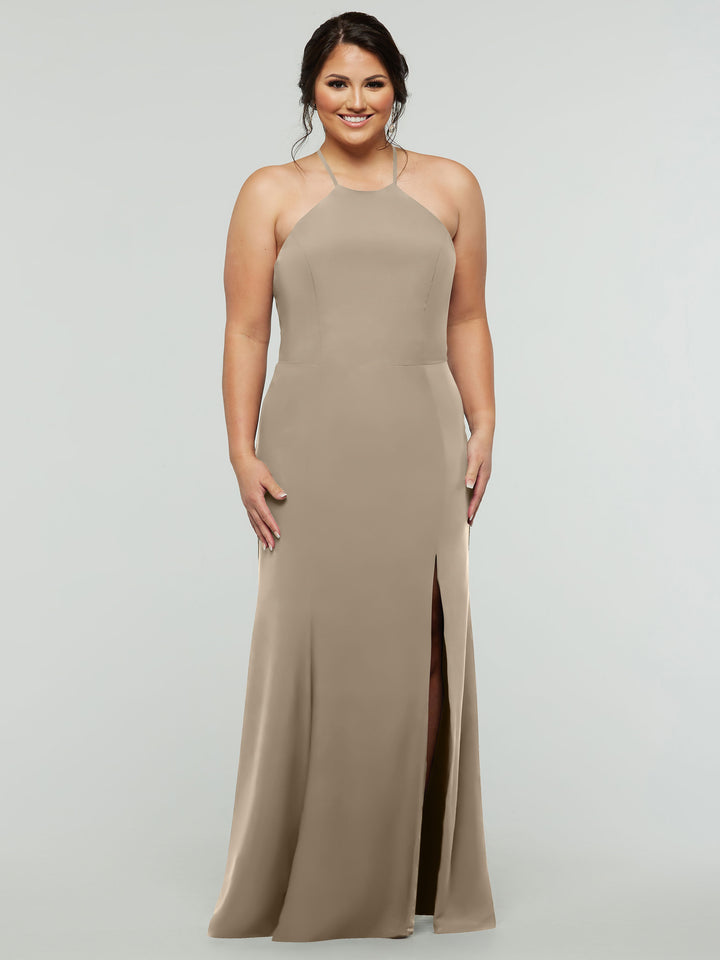 A woman smiles in the Avery Austin 83031, a fitted, floor-length taupe halter dress with a high neckline, strapped back, and thigh-high slit, set against a plain light gray background.