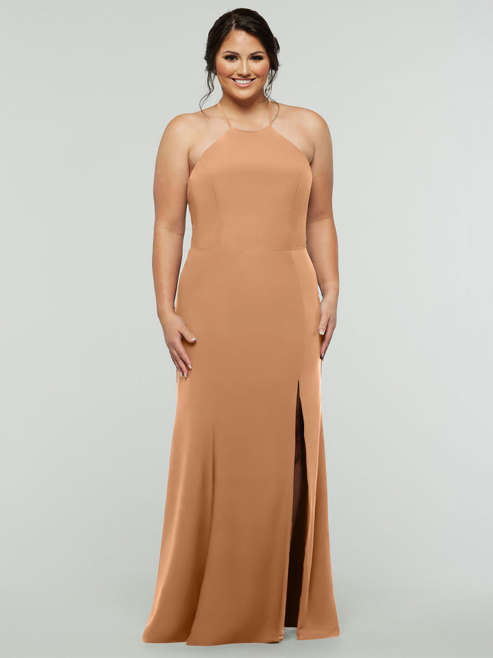 A woman smiles against a plain light gray background wearing Avery Austin 83031, a sleeveless, floor-length peach halter dress with a high neckline and thigh-high slit.