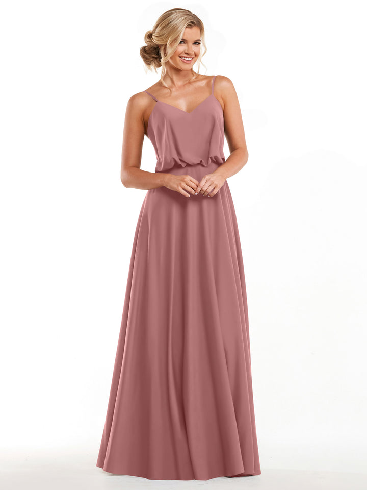 A woman with blond hair in a loose updo smiles against a white background, wearing Avery Austin 83040—a floor-length dusty rose A-line dress featuring thin straps and a flowy skirt.
