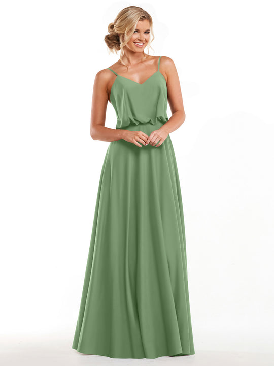 A woman with blonde hair styled in an updo is wearing Avery Austin’s sage green A-line dress, Product 83040, featuring thin straps and a flowy skirt, while smiling against a plain white background.