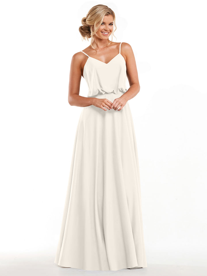 A woman stands smiling against a plain white background, wearing the Avery Austin 83040: a sleeveless, floor-length ivory A-line dress with thin straps, a relaxed bodice, and a fitted waist.
