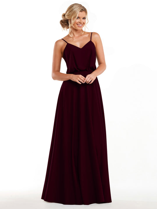 A woman in the Avery Austin 83040 dress—a sleeveless, floor-length burgundy A-line with thin straps and flowy skirt—smiles against a white background. Her blonde hair is styled in a loose updo.