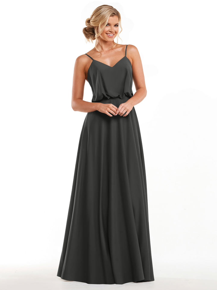 A woman models Avery Austin’s 83040: a sleeveless, slate-grey A-line dress with thin straps, V-neckline, and flowy floor-length skirt, standing and smiling against a plain white background.